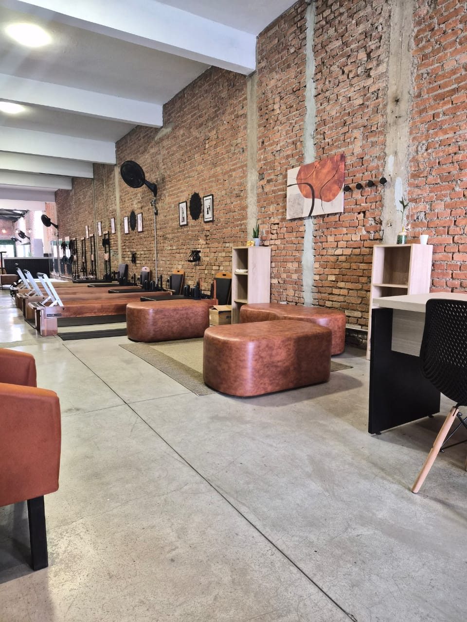 Sala do Studio Pilates Ventura com aparelhos MetaLife, parede de tijolo aparente e poltronas